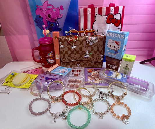 Beaded and charm bracelets displayed on a table with bags, a tumbler, nail sets and other assortment items.